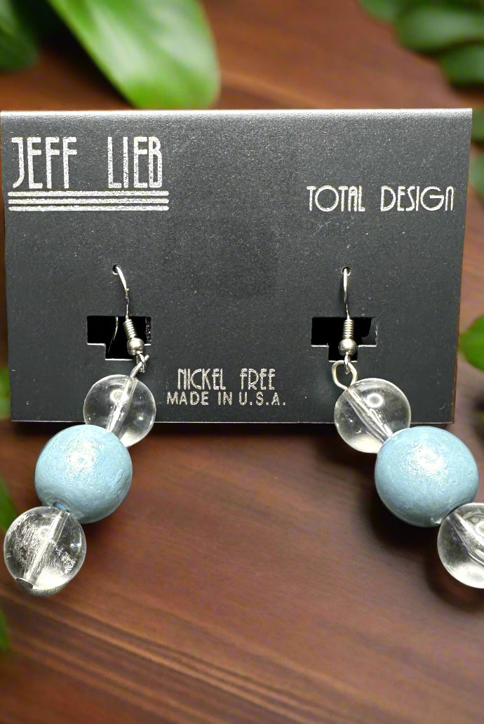 A pair of Jeff Lieb earrings with blue and clear beads on a card stand, indicating the earrings are nickel-free and made in the USA.